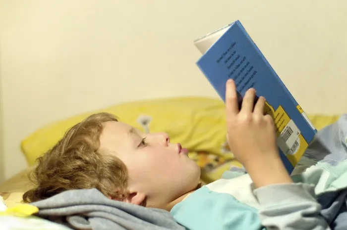 Impression encadrée : L'enfant lisant dans son lit.