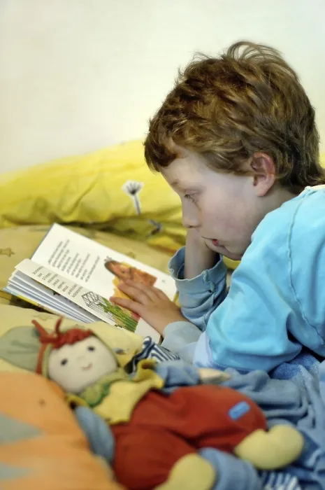 Impression encadrée : L'enfant lisant dans son lit. Impression encadrée : L'enfant lisant dans son lit.