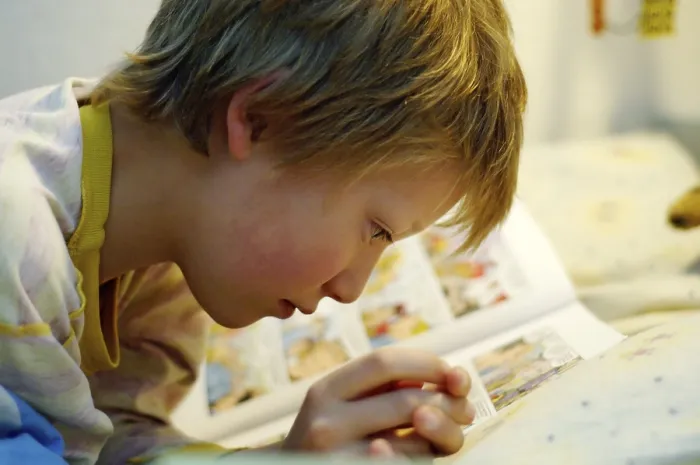 Impression encadrée : L'enfant lisant dans son lit. Impression encadrée : L'enfant lisant dans son lit.