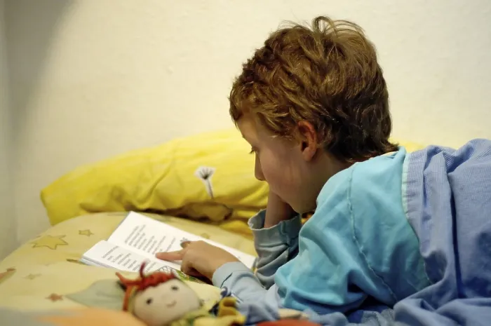 Impression encadrée : L'enfant lisant dans son lit.