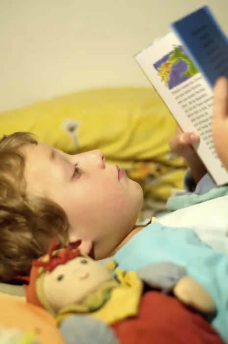 Impression encadrée : L'enfant lisant dans son lit. Impression encadrée : L'enfant lisant dans son lit.