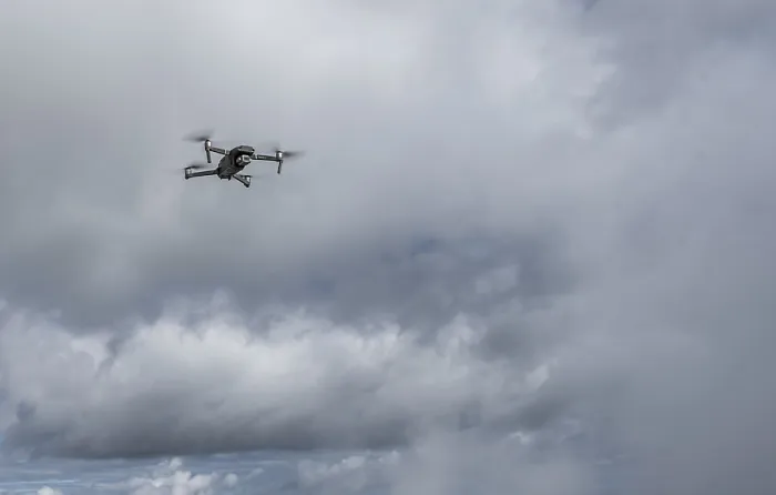 Impression encadrée : Un drone avec une caméra vole devant les nuages. Impression encadrée : Un drone avec une caméra vole devant les nuages.