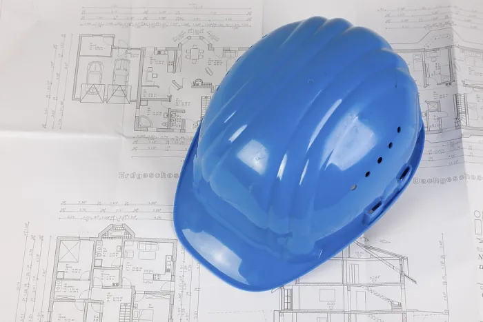 Impression encadrée : Chapeau de sécurité posé sur un plan de construction. Impression encadrée : Chapeau de sécurité posé sur un plan de construction.