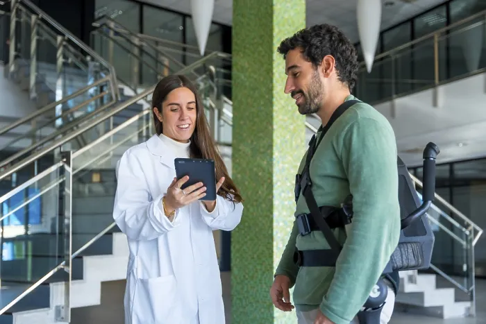 Impression encadrée : Exosquelette mécanique, physiothérapeute femme docteur parlant avec une tablette avec une personne handicapée et squelette robotique. Impression encadrée : Exosquelette mécanique, physiothérapeute femme docteur parlant avec une tablette avec une personne handicapée et squelette robotique.