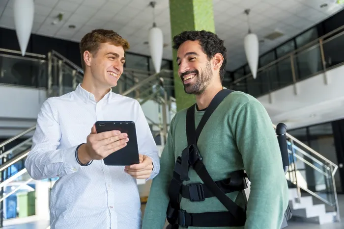 Impression encadrée : Exosquelette mécanique, physiothérapeute regardant consultation avec tablette avec personne handicapée avec squelette robotique.