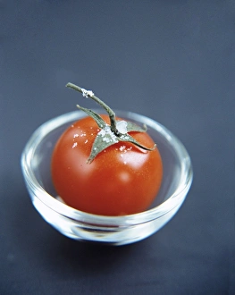 Impressions de Le tomate (Lycopersicon esculentum) dans un bol en verre. Ce fruit possède de nombreuses utilisations culinaires et est une bonne source de vitamines A et C Images datées de 2004 août: Tomato