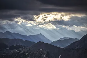 Sunset In Italy Impressions: Sun rays filter between black clouds at sunset