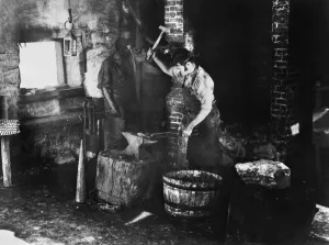 19th Century Occupations Impressions: BLACKSMITH AT WORK. A blacksmith and assistant at work. Undated photograph