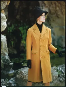 Mannequin féminine en train de poser dans un manteau jaune.