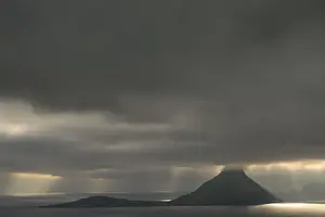 Un éclairage dramatique, des nuages bas, des rayons de lumière tombant sur la mer, Koltur, Utoyggjar, Îles Féroé, Danemark.
