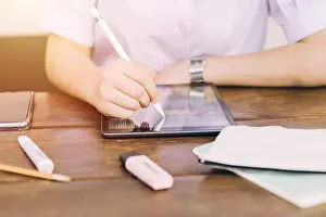 Élève d'école utilisant un appareil informatique tactile pour apprendre et écrire de la maison, technologie moderne pour l'éducation.
