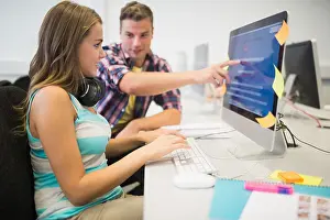 Des camarades souriants faisant un devoir ensemble dans la salle informatique.