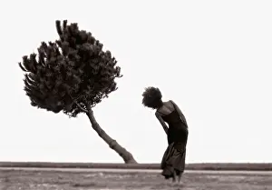 Femme dans paysage pliant son corps pour imiter un arbre qui se plie.