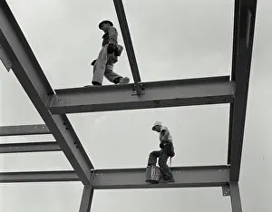 Low Angle View Photography Impressions: Two construction workers walking on the frame of a grain elevator