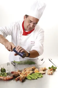 Crevette Royale Impressions: Le chef ajoute du poivre sur un gril teppan.