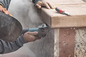 Male Construction Worker Impressions: Construction worker using grinder at construction site