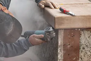 Male Construction Worker Impressions: Construction worker using grinder at construction site
