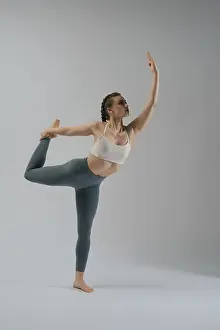 Minimalist Studio Shot Impressions: A dancer showcases her flexibility and strength while executing an elegant pose in a studio