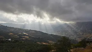 Greek Island Landscapes Impressions: Dramatic landscape with sun rays breaking through a cloud cover