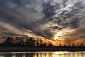 Natural Preserve In Eastern Germany Impressions: Dramatic sunset sky with trees and soft reflection in water