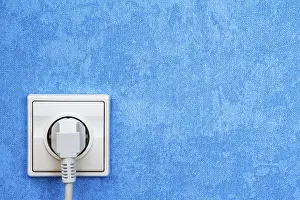 Power Supply Socket Impressions: Electrical plug connected into the socket on blue wall