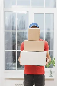 Parcel Delivery Impressions: Faceless courier with stack parcels
