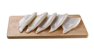 Seiche Impressions: Crevette fraîche crue ou filet de calmar sur plan de découpe isolé sur un fond blanc.