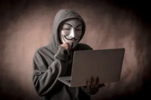 Hacker Anonymous Mask Impressions: Hacker with anonymous mask with a laptop thinking about programming