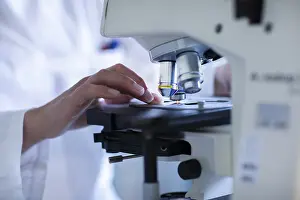 Female Lab Technician Impressions: Hand of a lab technician with microscope and sample working in a lab with light microscope