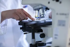 Working Clothes Europe Impressions: Hand of a lab technician with microscope and sample working in a lab with light microscope