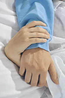 Couple In Bed Impressions: Two hands are held together on bed sheets