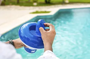 Swimming Pool Disinfection Impressions: Hands of a worker installing a pool chlorine float