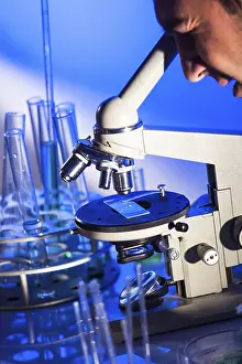 Laboratory Equipment Usage Impressions: Man is looking into the ocular of microscope