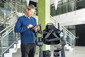 Mechanical Exoskeleton Impressions: Mechanical exoskeleton computer engineer looking at the robot with a tablet