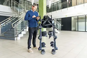 Physiotherapy Robot Impressions: Mechanical exoskeleton computer engineer looking at the robot with a tablet