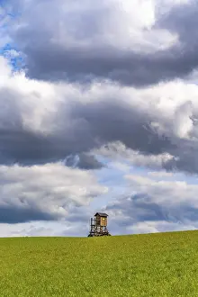 Cloudy Landscape Impressions: Mobile raised hide in an empty field under dramatic clouds