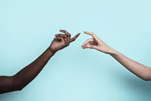 Diversity And Inclusion Impressions: Two multiethnic hands reach toward each other against a solid blue backdrop