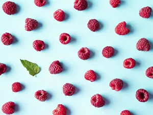 Flat Lay Fruit Photography Impressions: Pattern of ripe red raspberry on blue background