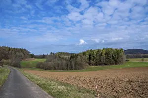 Cloudy Countryside Scene Impressions: Paved road cutting through spring fields