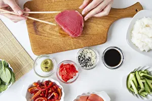 Impressions de Le processus de préparation du sushi, la préparation de tous les ingrédients pour le sushi, la fille tient du thon avec des baguettes Thon Impressions: Le processus de préparation du sushi.