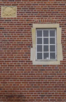 Red Brick Facade Impressions: A rectangular window and a coat of arms in a red brick facade