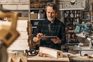 Male Craftsman Impressions: Senior carpenter using a digital tablet in his workshop