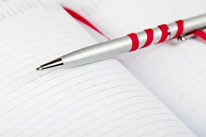 Uninhabited Office Space Decor Impressions: Silver pen on opened notebook with red string