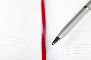 Office Supply Desk Utensils Impressions: Silver pen on opened notebook with red string