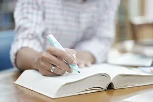 Laptop Computer Use Impressions: A student writes notes in a notebook while studying in a library