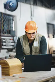 Carpenter Workshop Impressions: Successful worker using a computer in the carpentry workshop