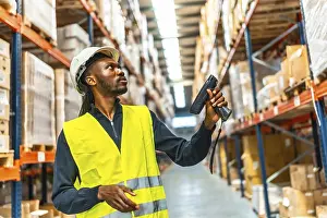 Supply Chain Management Impressions: Side view of an african worker scanning package with bar code reader in a distribution warehouse