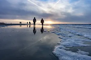 Evening Sun Germany Impressions: Walkers at sunset on the beach