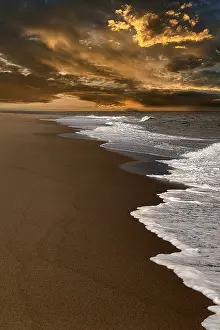 US American Coastal Landscape Impressions: Waves on empty beach, dramatic cloudy sky at sunset
