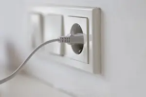Power Supply Concept Impressions: White power plug in a socket on the wall